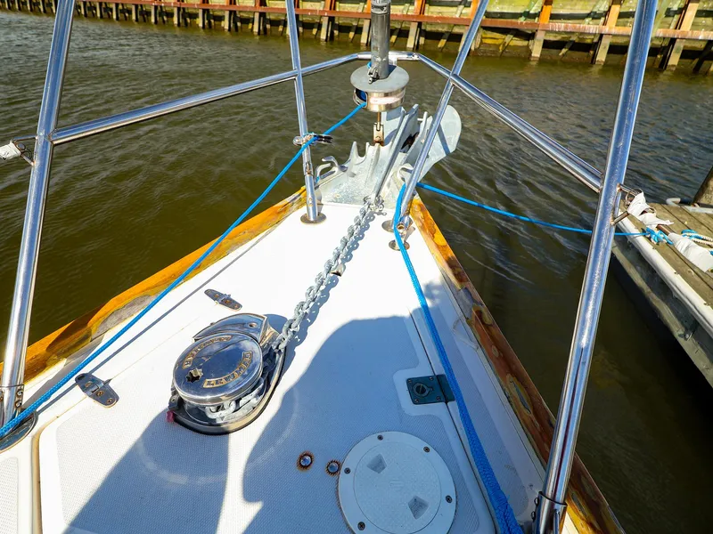 Slide: The Image of Bow of 1987 Sabre 36 Sloop with anchor chain and winch, docked by wooden pier. - 9