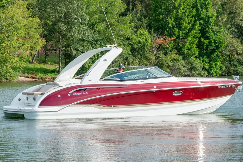 Slide: The Image of 2012 Formula 310 Bowrider boat cruising on a serene lake with lush green trees. - 4