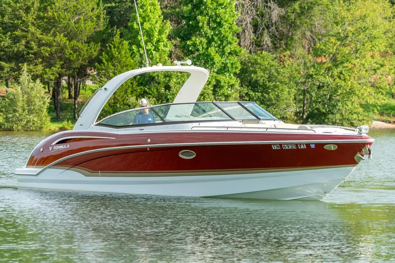 Slide: The Image of 2012 Formula 310 Bowrider boat cruising on a serene lake with lush green trees. - 6
