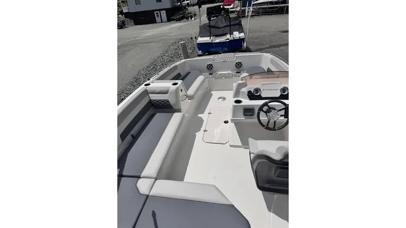 Slide: The Image of 2025 Starcraft SVX 171 OB boat interior with seating and steering wheel, parked outdoors. - 10