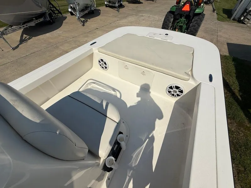 Slide: The Image of 2015 Key West 177 Skiff interior with seating and storage, parked near other boats and a tractor. - 9