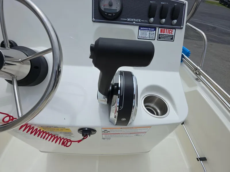 Slide: The Image of 2024 Boston Whaler 150 Montauk steering console with throttle and cup holder. - 10