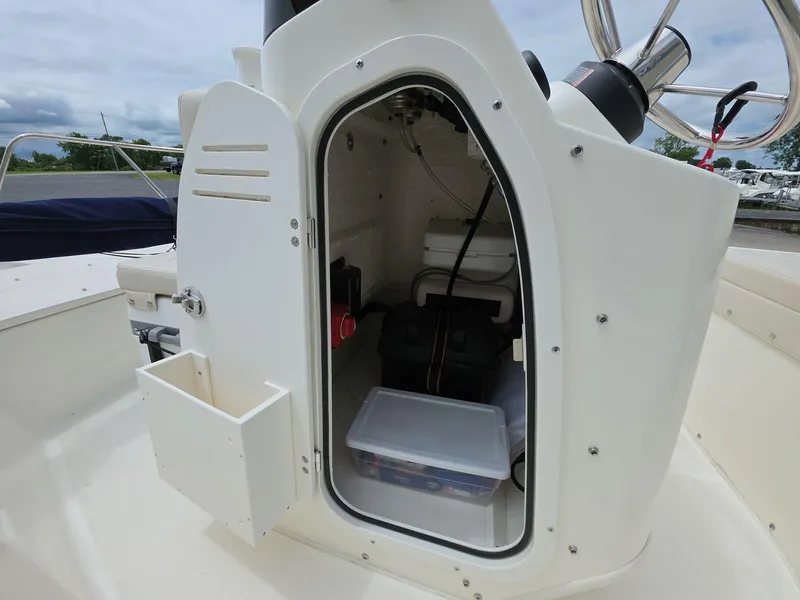 Slide: The Image of 2024 Boston Whaler 150 Montauk storage compartment with open door, showcasing interior equipment. - 11