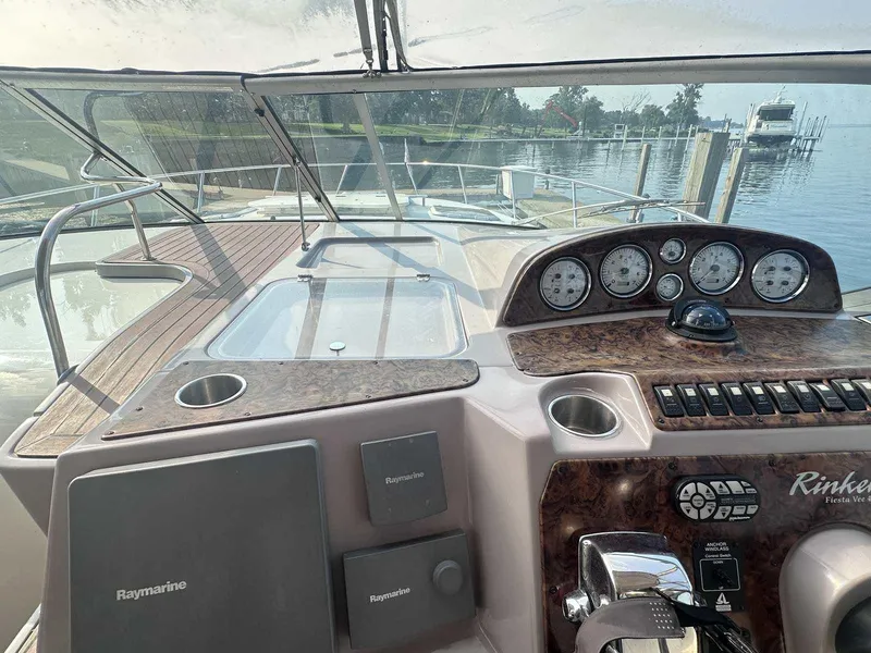 Slide: The Image of 2004 Rinker Fiesta Vee 410 helm with Raymarine electronics and wood finish, docked by the water. - 14