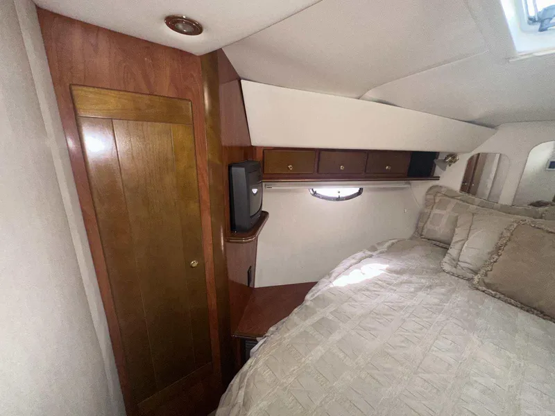 Slide: The Image of 2004 Rinker Fiesta Vee 410 cabin interior with bed, wooden cabinetry, and small window. - 31