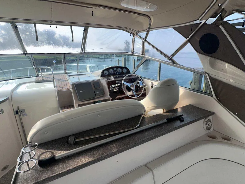 Slide: The Image of 2004 Rinker Fiesta Vee 410 boat cockpit with steering wheel and dashboard, docked by water. - 7