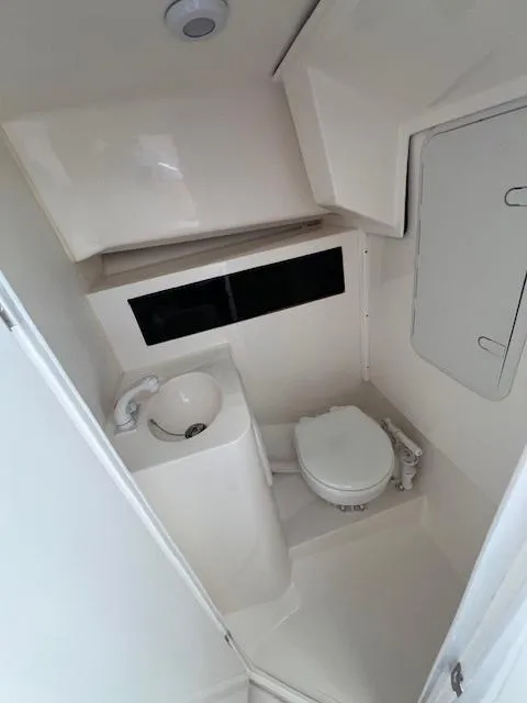 Slide: The Image of Compact bathroom in 2026 NorthCoast 255 HT boat, featuring toilet and sink. - 11