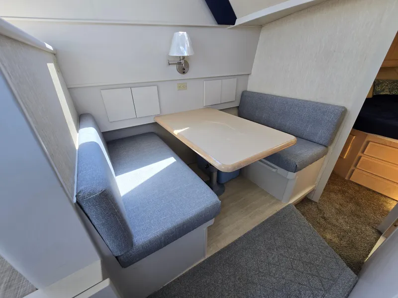 Slide: The Image of Cozy dining area in 1998 Henriques 38 Sportfisherman with blue cushioned seating and wooden table. - 13
