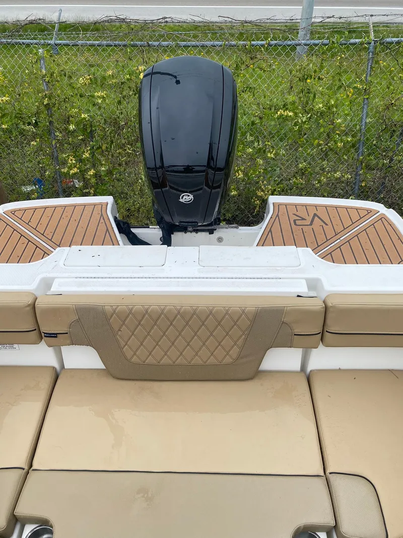 Slide: The Image of 2025 Bayliner VR4 Bowrider OB with tan seating and outboard motor, docked near a fence. - 14
