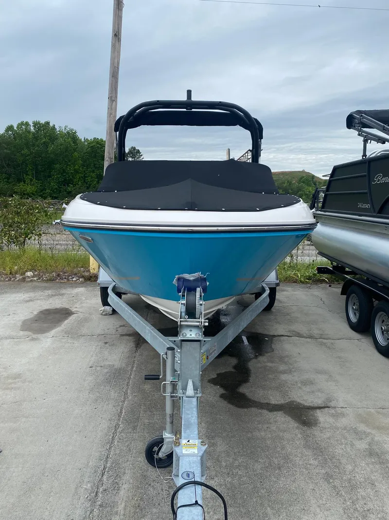 Slide: The Image of 2025 Bayliner VR4 Bowrider OB on trailer, blue hull, parked outdoors. - 2