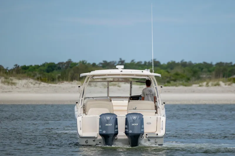 Slide: The Image of 2020 Grady-White Freedom 307 boat cruising on open water near a sandy shoreline. - 2