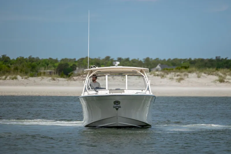 Slide: The Image of 2020 Grady-White Freedom 307 boat cruising on calm water near a sandy shoreline. - 6