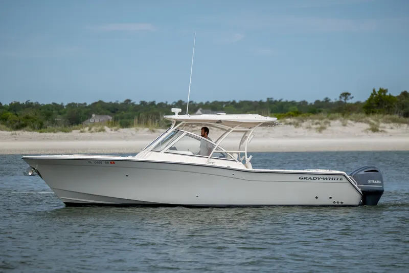 Slide: The Image of 2020 Grady-White Freedom 307 boat cruising near a sandy shoreline. - 7