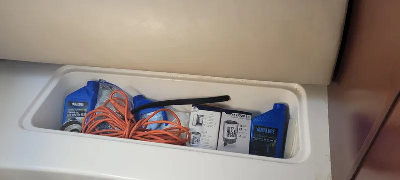 Slide: The Image of Storage compartment with Yamalube oil, orange extension cord, and filter box in a 2015 Century 30 boat. - 45
