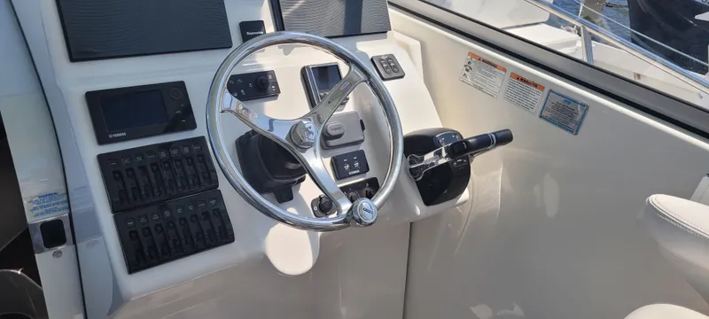 Slide: The Image of Control panel of a 2015 Century 30 boat with steering wheel and navigation instruments. - 13
