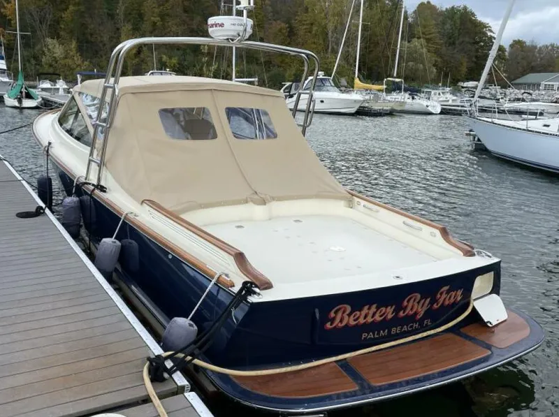 Slide: The Image of 2012 Hinckley Talaria boat docked, featuring a beige canopy and wooden accents. - 1
