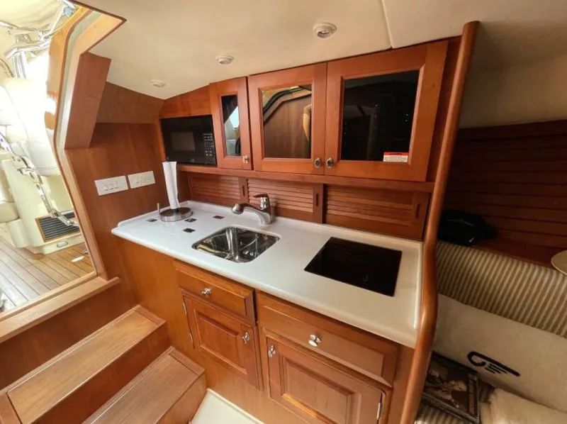 Slide: The Image of Hinckley Talaria 2012 yacht interior with wooden cabinetry, sink, and stovetop. - 10