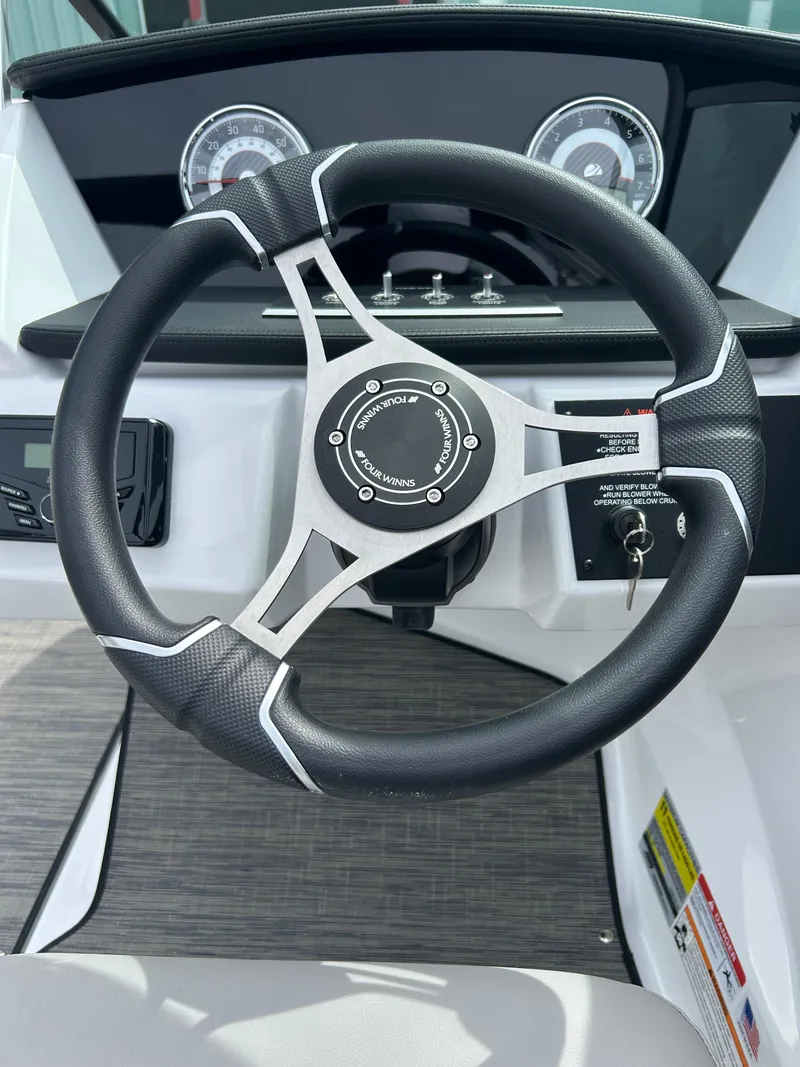 Slide: The Image of Steering wheel of 2025 Four Winns H1 Freedom boat, featuring modern dashboard design. - 12