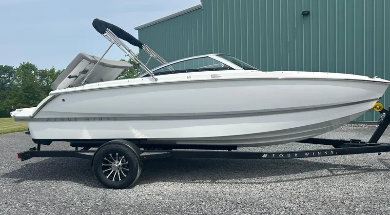 Slide: The Image of 2025 Four Winns H1 Freedom boat on trailer, parked outdoors. - 2