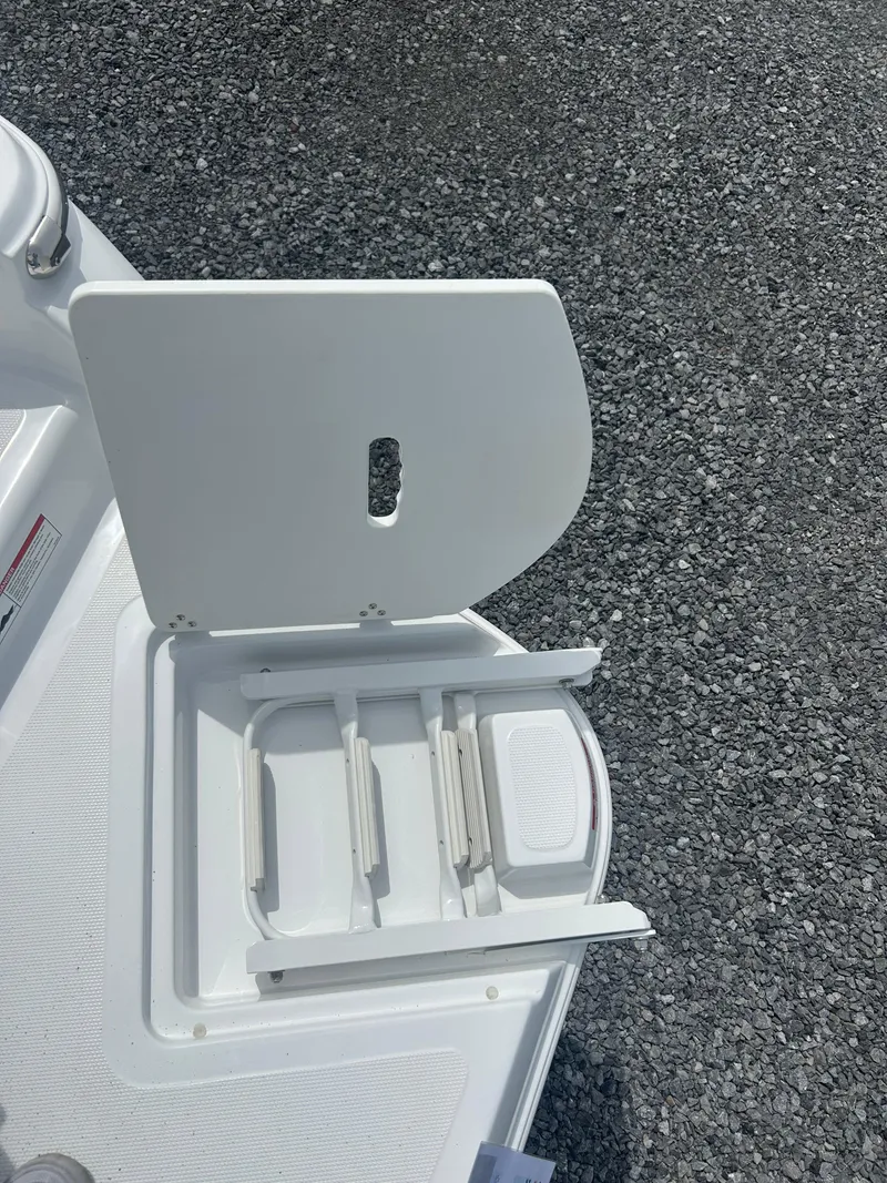 Slide: The Image of 2025 Four Winns H1 Freedom boat compartment with open hatch on textured surface. - 9