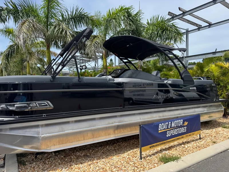 Slide: The Image of 2025 Avalon Catalina Platinum Quad Lounge boat displayed at dealership, surrounded by palm trees. - 2