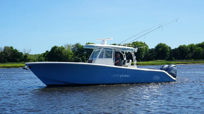 Slide: The Image of 2022 Cobia 350 Center Console boat on water, clear sky, lush green background. - 14