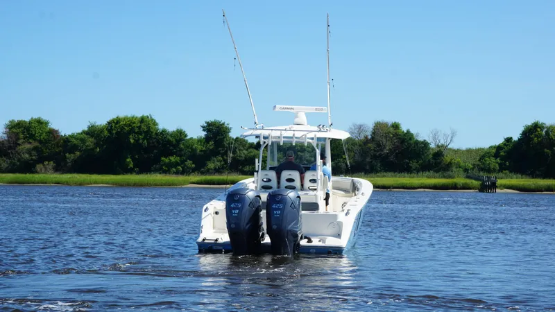 Slide: The Image of 2022 Cobia 350 Center Console boat on water with twin engines, lush greenery in background. - 4