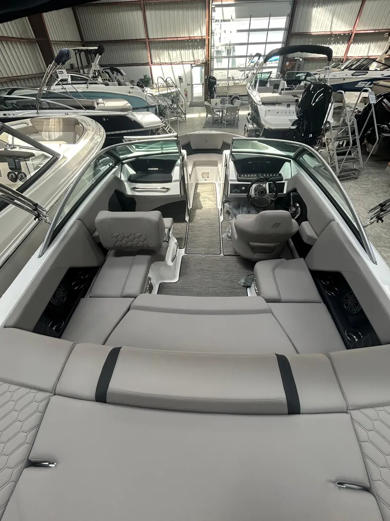 Slide: The Image of 2025 Four Winns H2 boat interior with modern seating and dashboard in a showroom. - 12