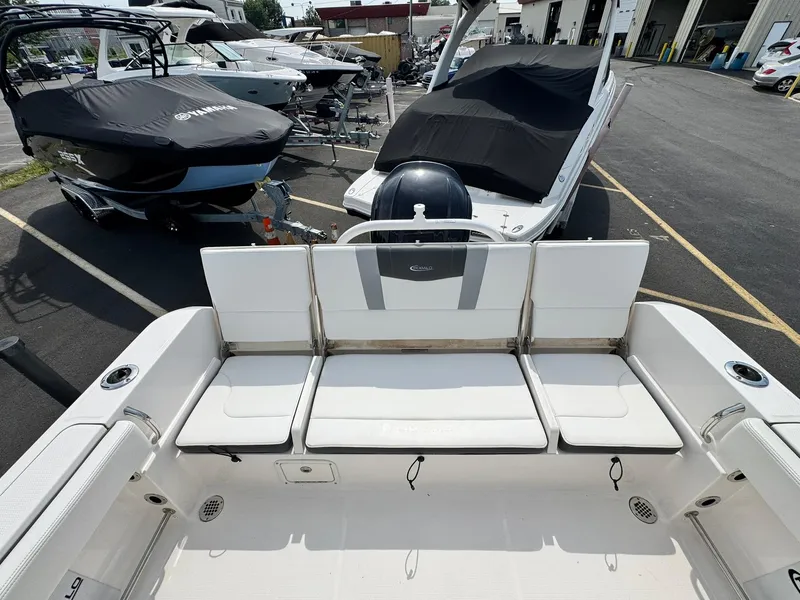 Slide: The Image of 2022 Robalo R230 Center Console boat interior with seating, parked in a marina. - 21