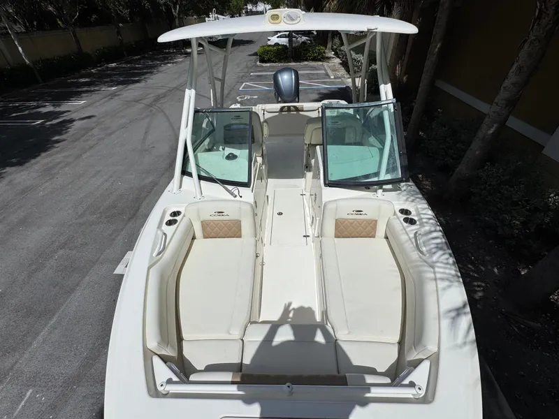Slide: The Image of 2021 Cobia 240 Dual Console boat with open seating and windshield, parked outdoors. - 16