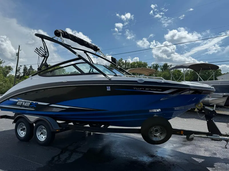 Slide: The Image of 2016 Yamaha Boats 212X on trailer, blue and black design, parked outdoors under cloudy sky. - 5