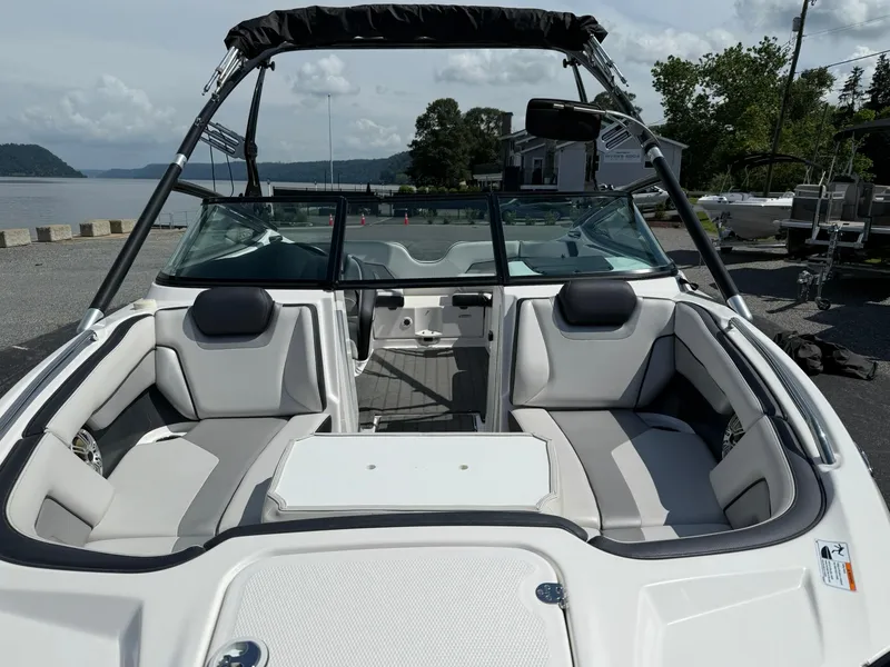 Slide: The Image of 2016 Yamaha Boats 212X interior with seating, docked by a scenic waterfront. - 6