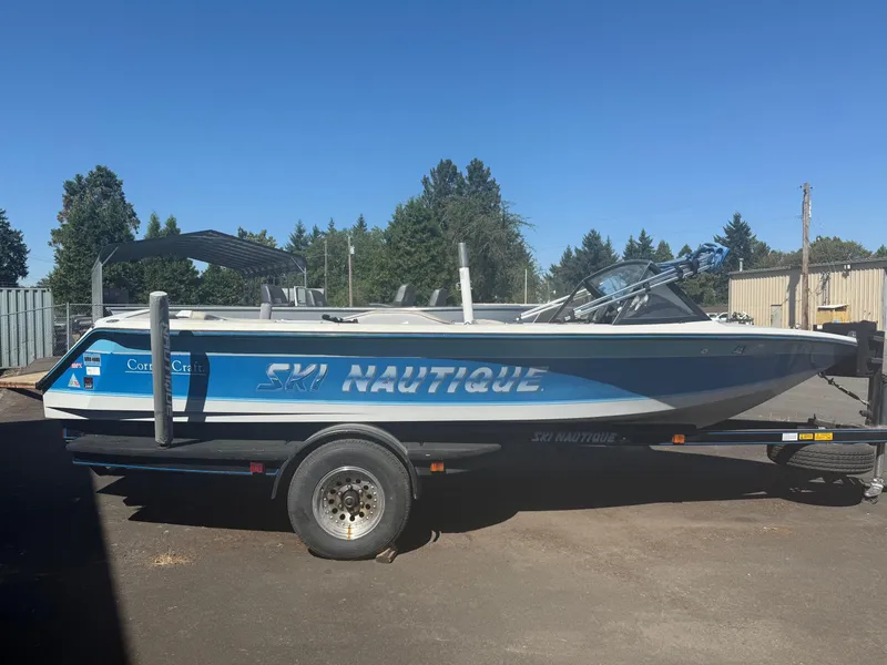 Slide: The Image of 1991 Correct Craft Ski Nautique 196 boat on trailer, blue and white design, outdoors. - 3
