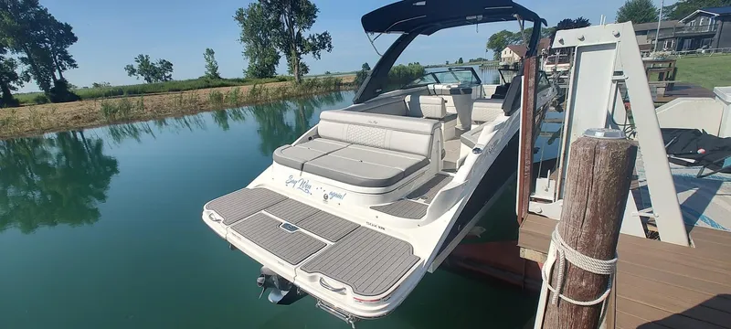 Slide: The Image of 2023 Sea Ray SDX 270 boat docked on a serene lake with lush greenery. - 3