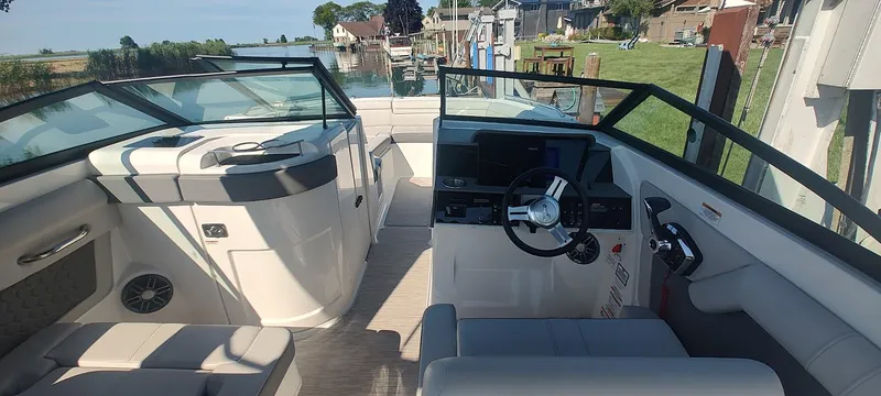 Slide: The Image of 2023 Sea Ray SDX 270 boat interior with modern helm and seating, docked by a scenic waterfront. - 6