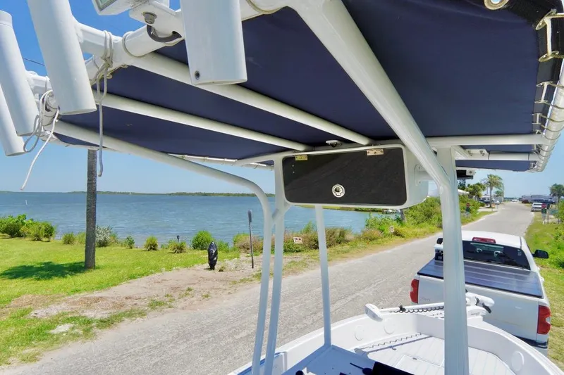 Slide: The Image of 2003 Key Largo 186 CC boat with canopy, parked near a scenic waterfront road. - 11