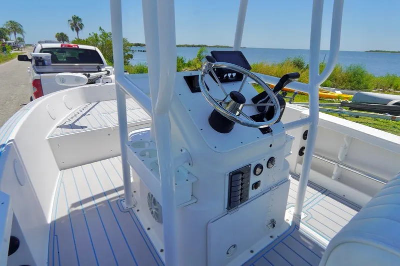 Slide: The Image of 2003 Key Largo 186 CC boat interior with steering wheel, docked near a scenic waterfront. - 12