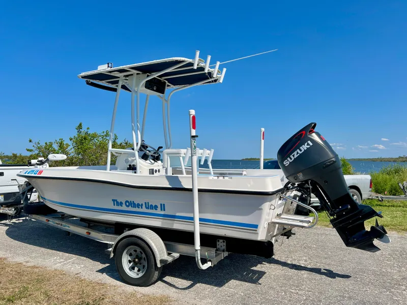 Slide: The Image of 2003 Key Largo 186 CC boat on trailer with Suzuki outboard motor, parked near water. - 25