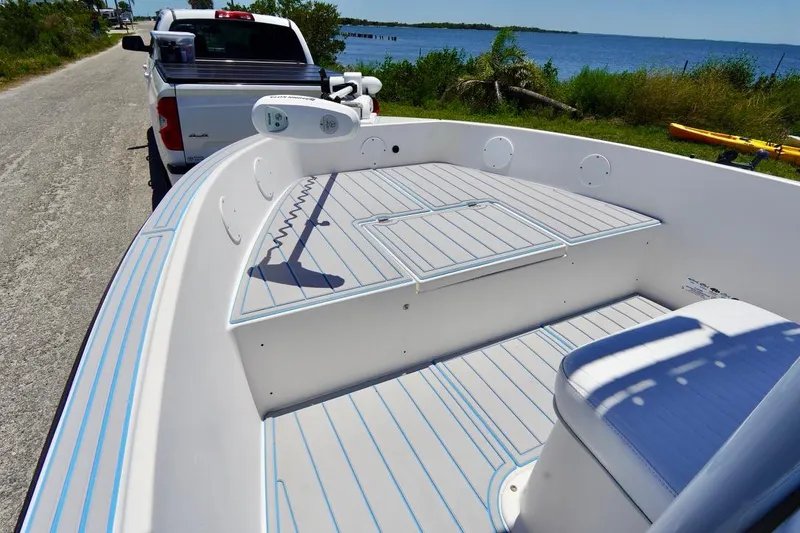 Slide: The Image of 2003 Key Largo 186 CC boat on trailer by waterfront road, clear blue sky. - 3