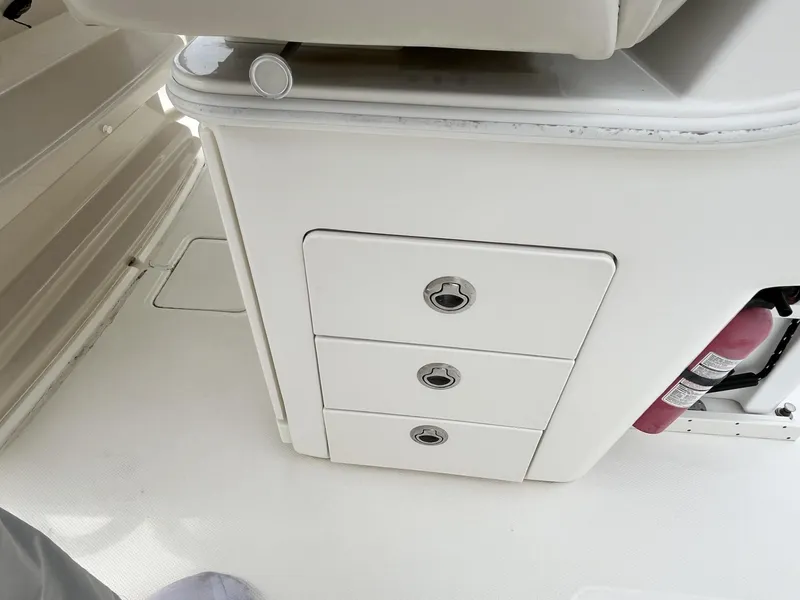 Slide: The Image of 2018 Boston Whaler 330 Outrage interior with storage drawers and fire extinguisher. - 16