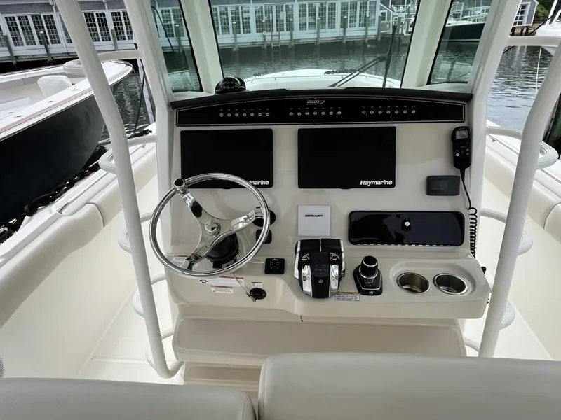 Slide: The Image of 2018 Boston Whaler 330 Outrage helm with steering wheel and navigation controls. - 19