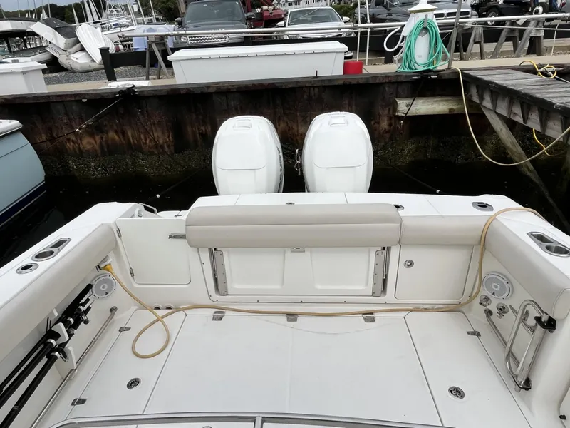 Slide: The Image of 2018 Boston Whaler 330 Outrage boat docked, featuring dual outboard engines. - 8