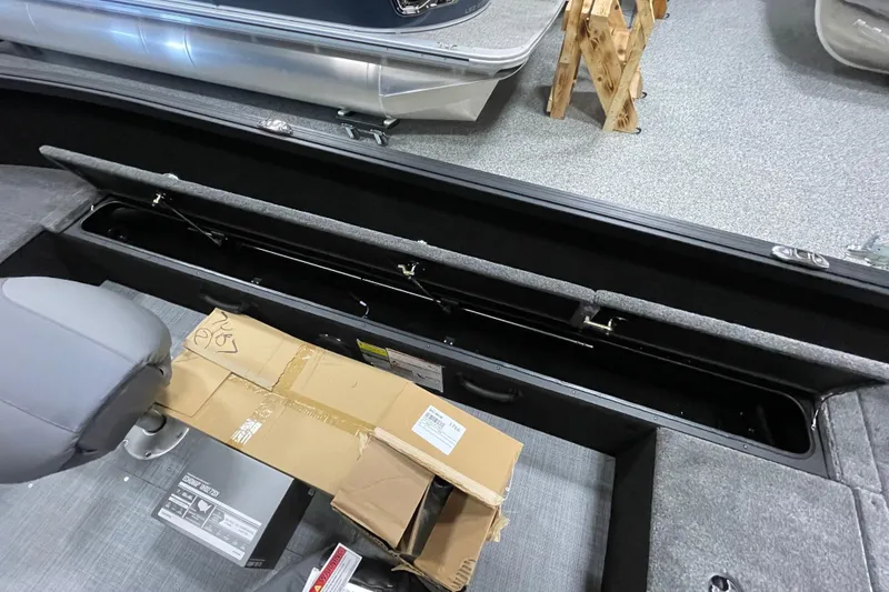 Slide: The Image of 2026 Alumacraft Competitor 185X Tiller boat interior with open storage compartment and packaging. - 16