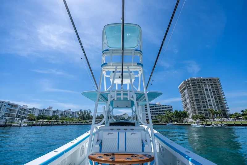 Slide: The Image of 2016 Yellowfin 39 Offshore boat on water, with cityscape background under clear blue sky. - 21