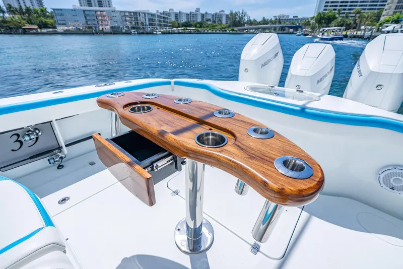 Slide: The Image of 2016 Yellowfin 39 Offshore boat with wooden rod holder, Mercury engines, and scenic waterfront view. - 7