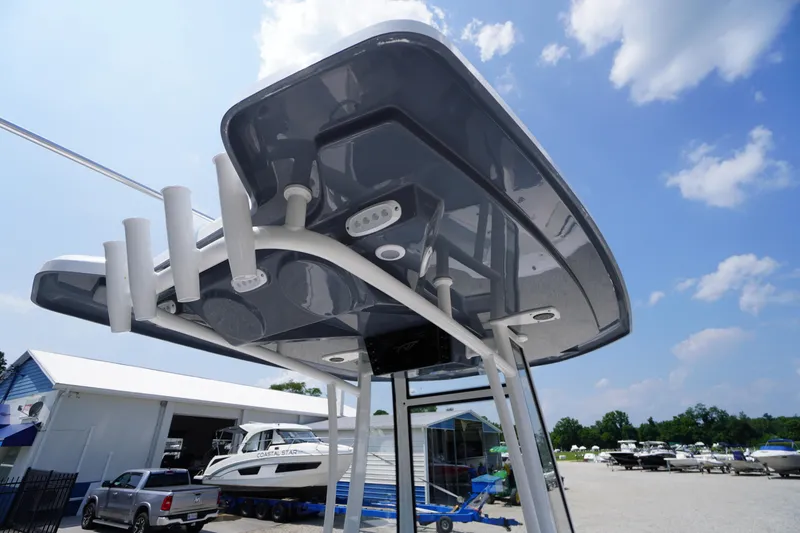 Slide: The Image of 2026 Tidewater 198 CC Adventure boat with T-top, parked outdoors under a blue sky. - 20