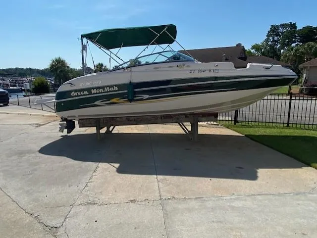 Slide: The Image of 2006 Four Winns 244 Funship boat with green canopy on a trailer in a driveway. - 1