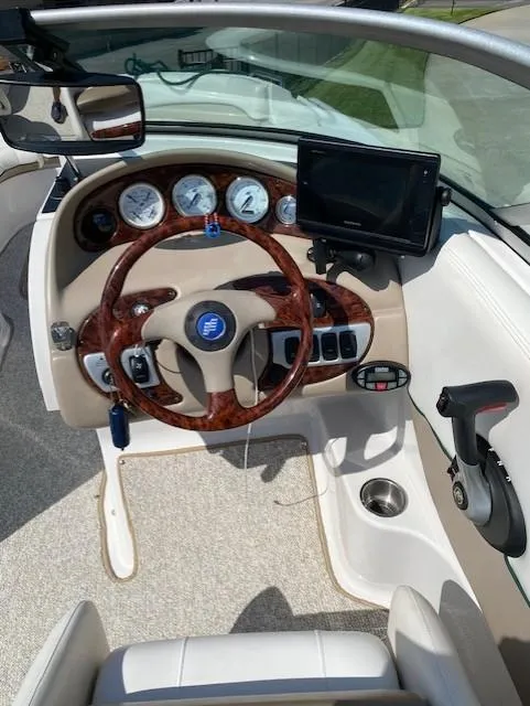 Slide: The Image of 2006 Four Winns 244 Funship boat dashboard with wood accents and modern controls. - 5