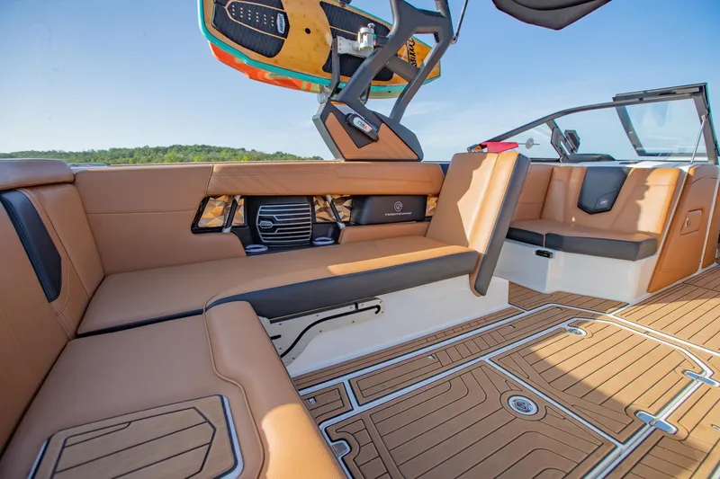 Slide: The Image of 2020 Nautique Super Air Nautique G25 interior with tan seating and wakeboard rack. - 15