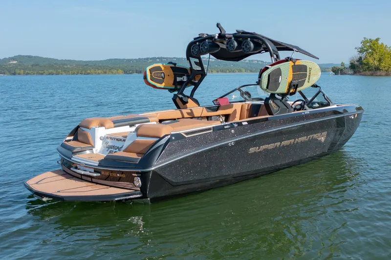 Slide: The Image of 2020 Nautique Super Air Nautique G25 boat on a lake, featuring sleek design and wakeboard racks. - 5